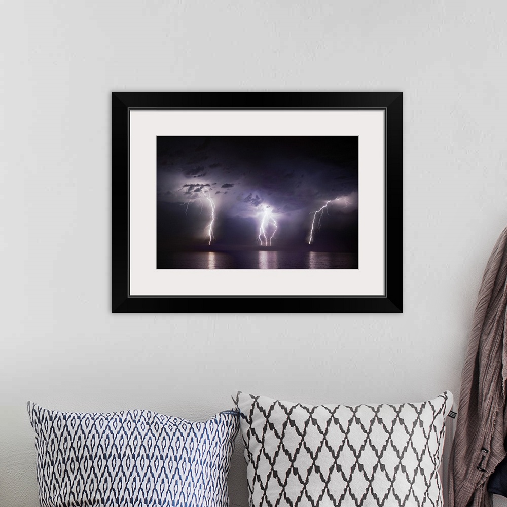 A bohemian room featuring Time-lapse photo of three bolts of lightning striking the ocean from storm clouds at night, illum...