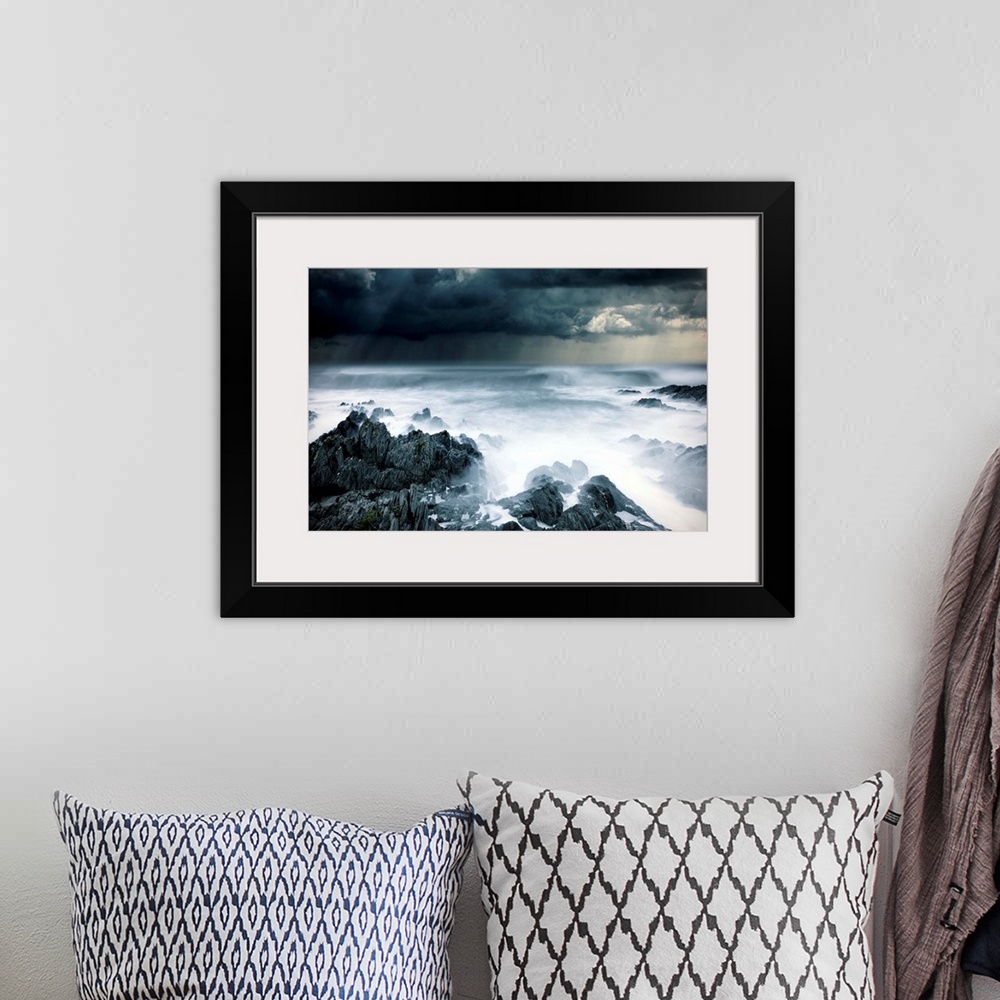 A bohemian room featuring Stormy seascape with rough surf and dark clouds and rocks