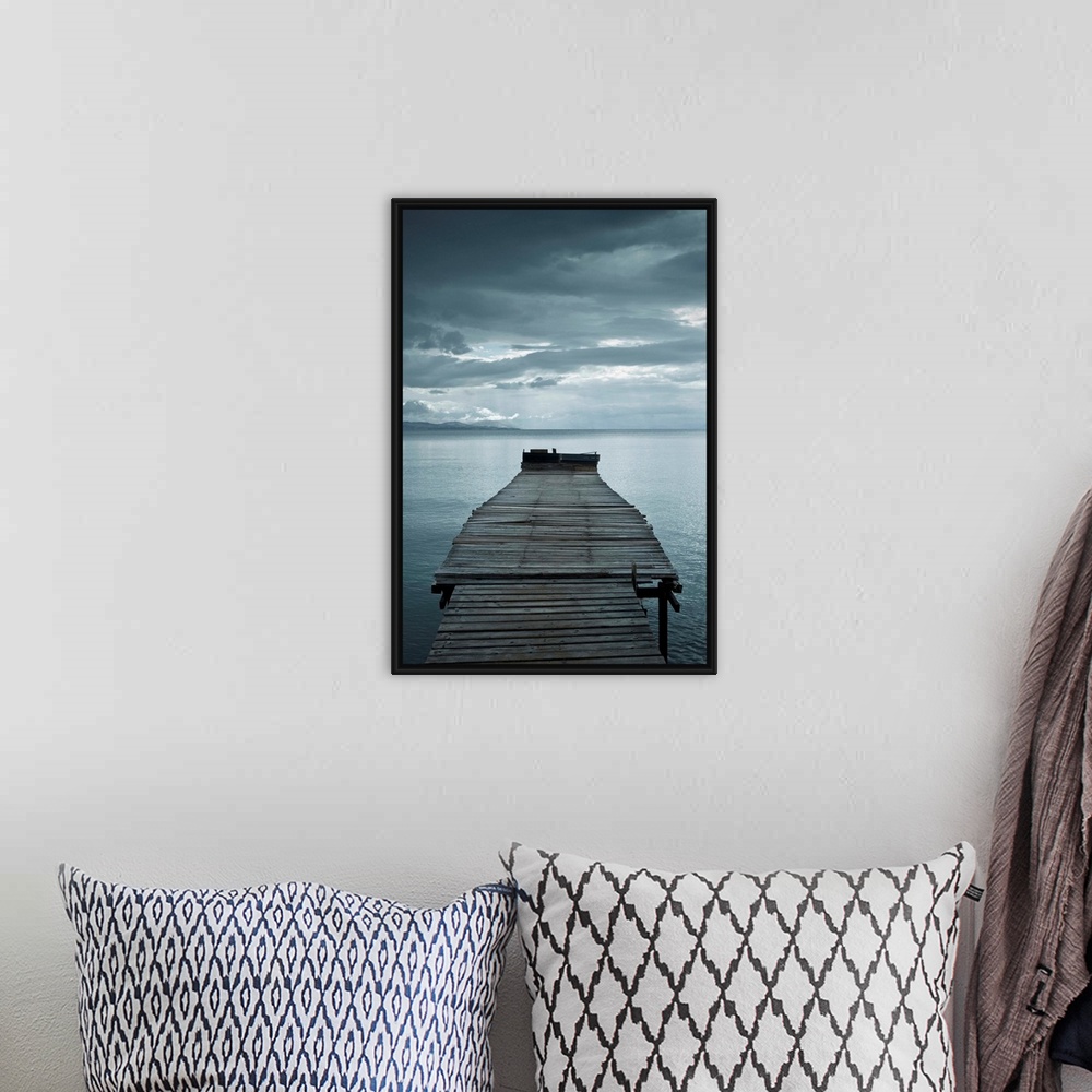 A bohemian room featuring Photograph of a weathered dock over calm water with dark clouds overhead.