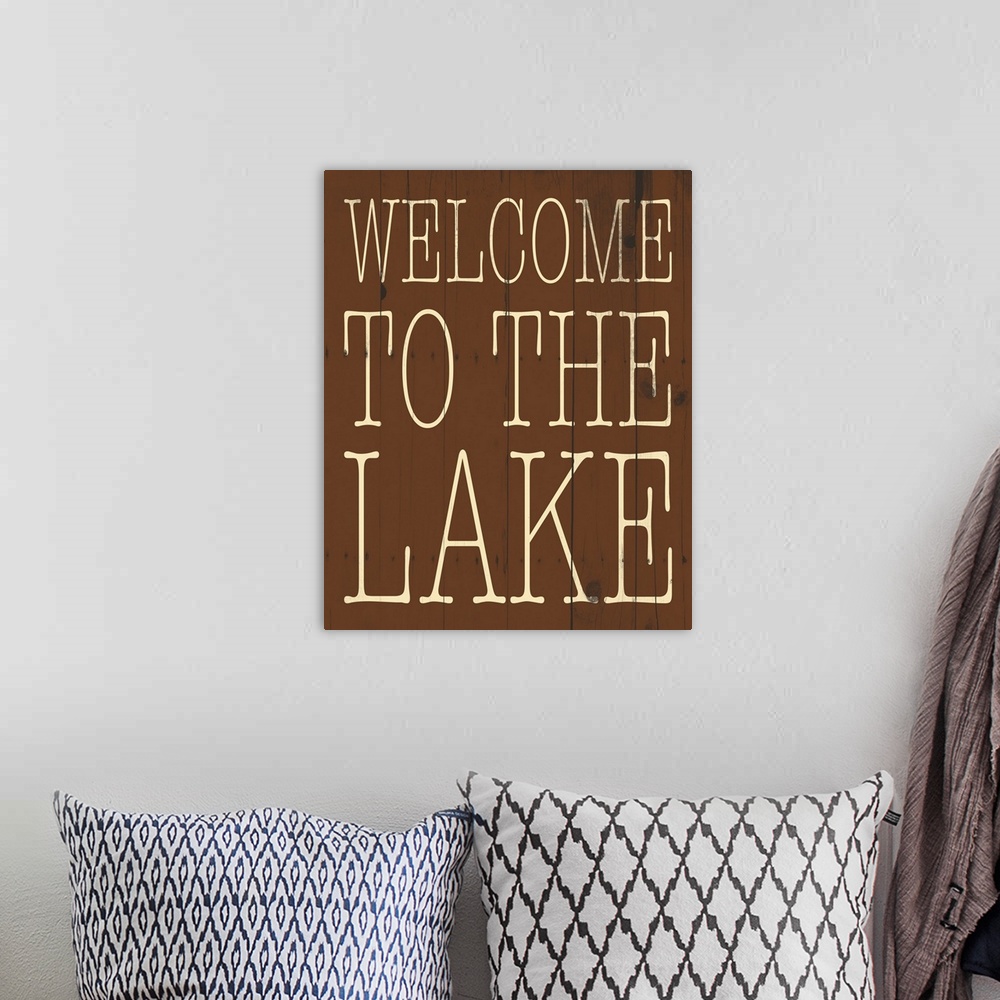 A bohemian room featuring Typographical artwork with "Welcome to the lake" in a thin rustic text.