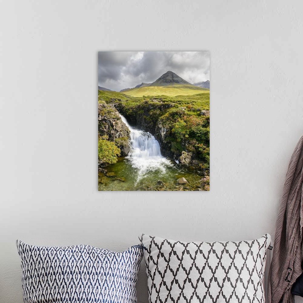 A bohemian room featuring A photograph of a Scottish landscape with a mountain in the distance and a waterfall in the foreg...