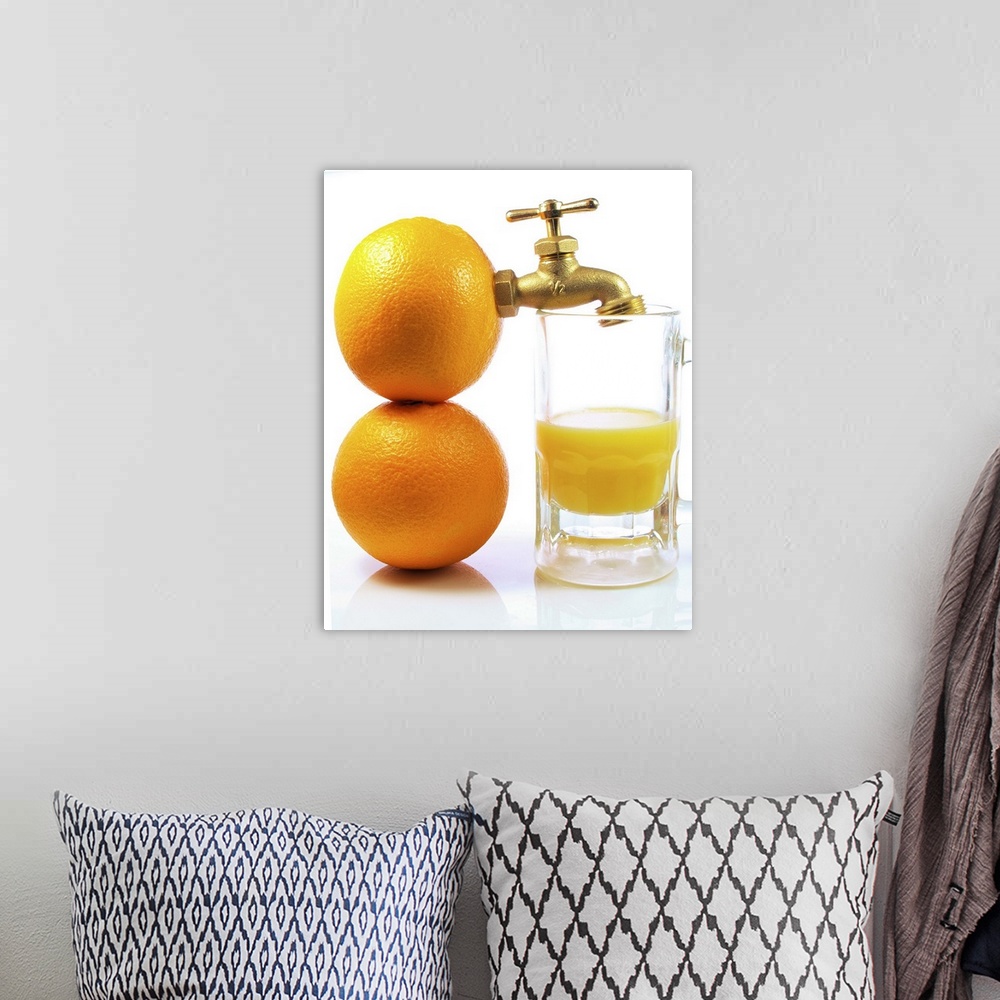 A bohemian room featuring Two oranges with spigot attached next to glass of orange juice on white background.