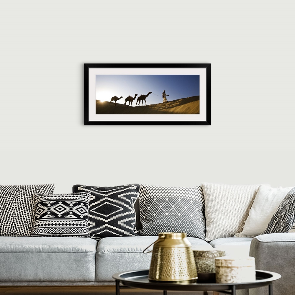 A bohemian room featuring Man walking camels through the desert in India