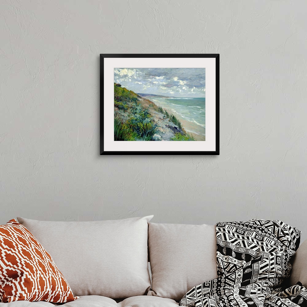 A bohemian room featuring Impressionist landscape painting of the beach and a sea cliff covered in grass on a cloudy day.