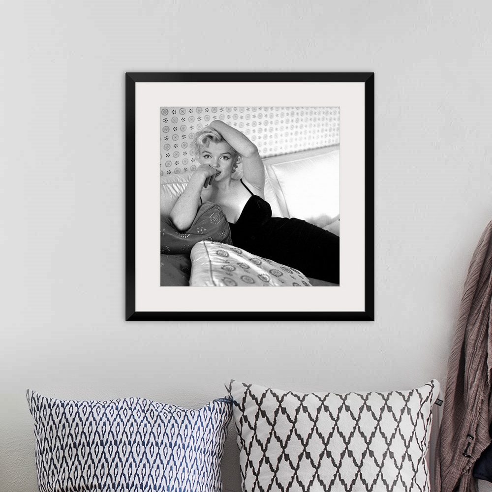 A bohemian room featuring Wall art of Marilyn Monroe sitting on a sofa looking at the camera.