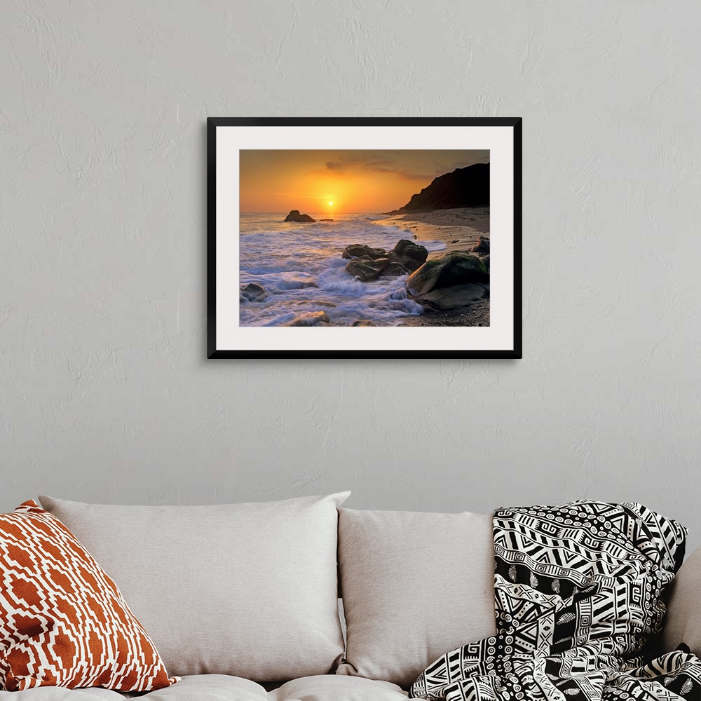 A bohemian room featuring Large landscape photograph of a golden sunset over the rocky shoreline at Leo Carrillo State Beac...