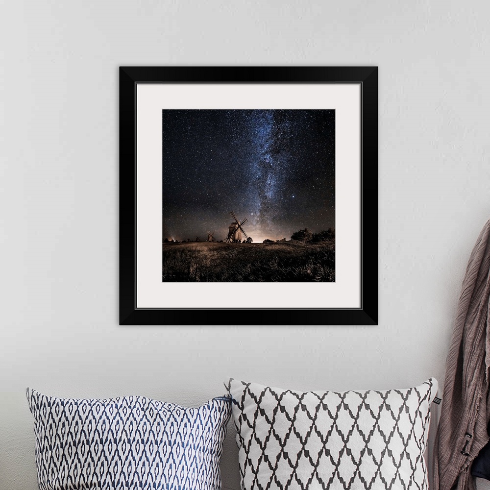 A bohemian room featuring A dramatic photograph of a countryside scene with windmills in the distance and a starry night sk...