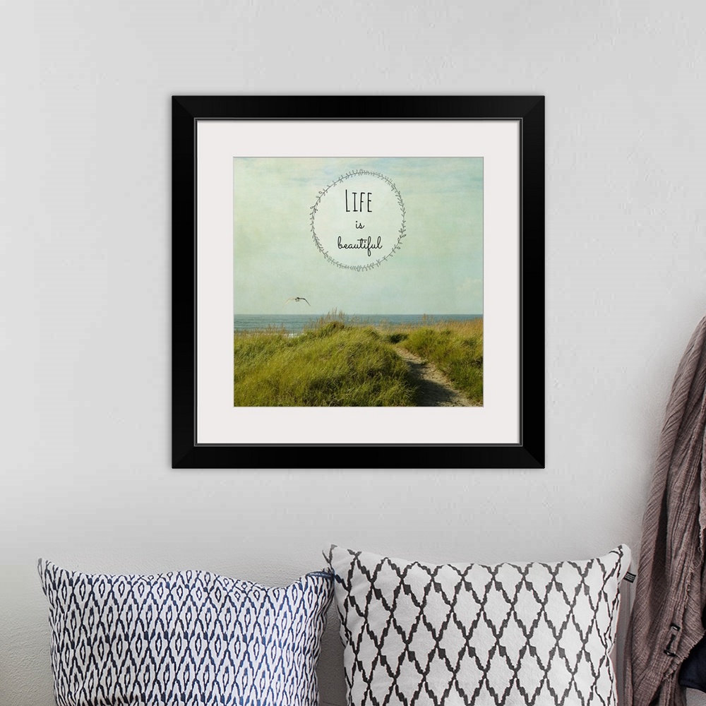 A bohemian room featuring "Life Is Beautiful" written inside a leafy circle on top of a square photograph of a grassy dune ...