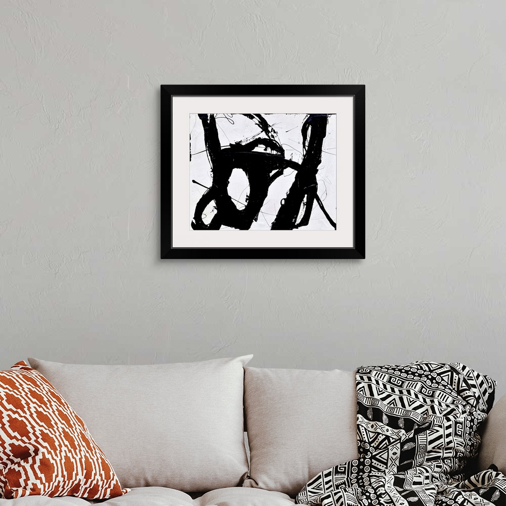 A bohemian room featuring A contemporary abstract painting of bold black lines swirling against a white background.
