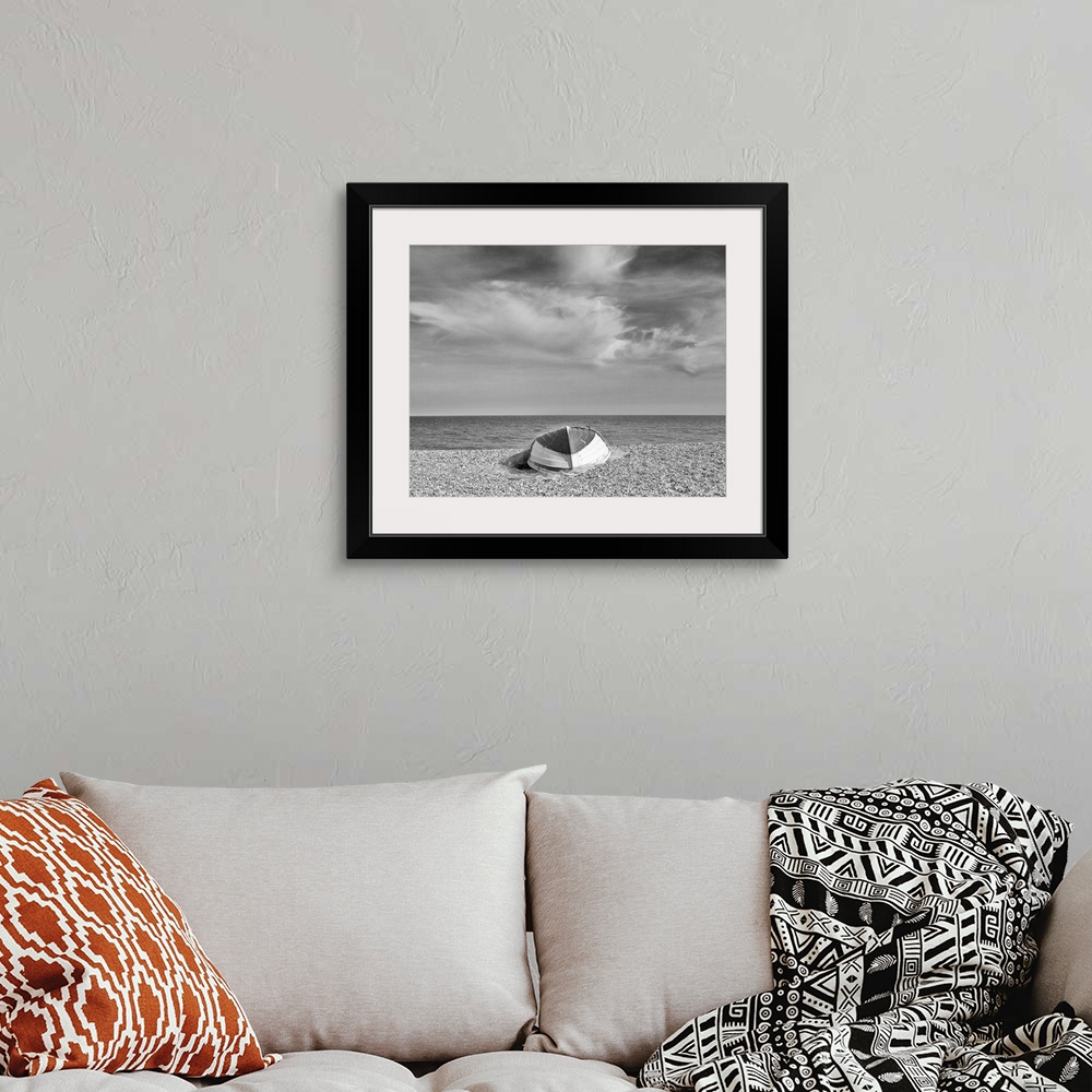 A bohemian room featuring A monochrome black and white image of an upturned rowing boat on an English shingle beach in brig...