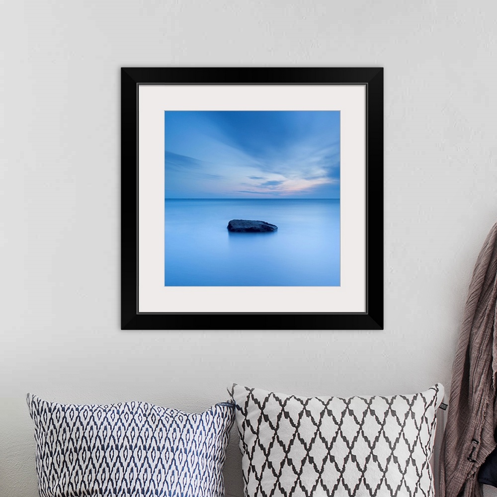 A bohemian room featuring A zen calm minimal minimalist cool deep blue image of one rock in a flat calm sea.