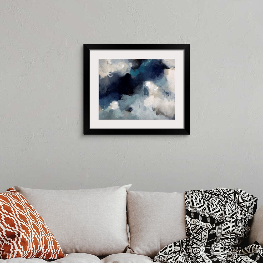 A bohemian room featuring Abstract painting of what almost looks like fluffy white clouds in an aggressive dark sky.
