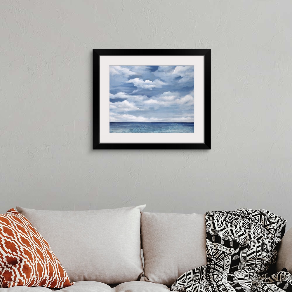 A bohemian room featuring Contemporary artwork of a serene ocean view with bright clouds above.