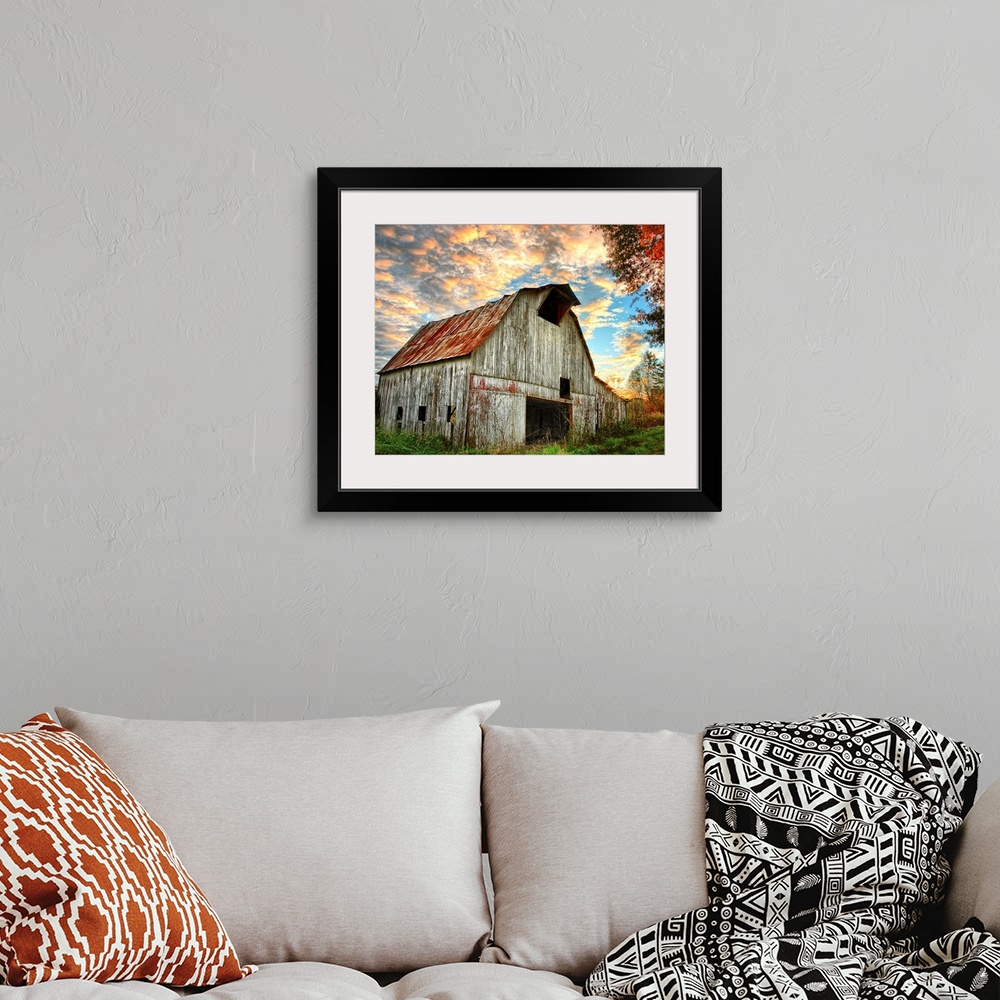 A bohemian room featuring Sunset over an old, weathered barn, with a cloudy sky.