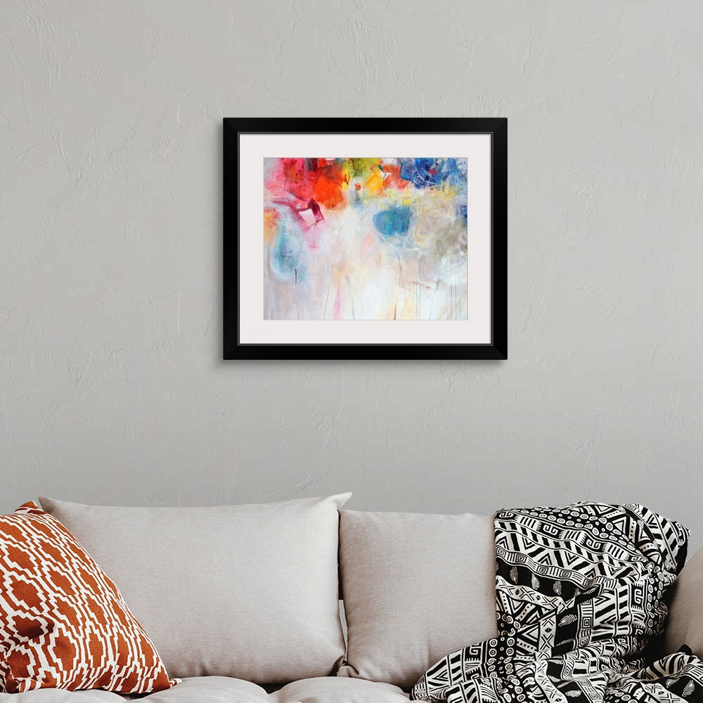 A bohemian room featuring Contemporary abstract painting of bright multi-colored forms overtop a neutral background.