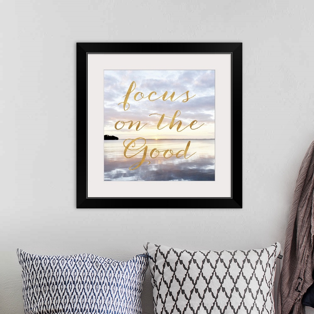 A bohemian room featuring "Focus on the good" hand written in gold letters over an image of the sea at dawn.