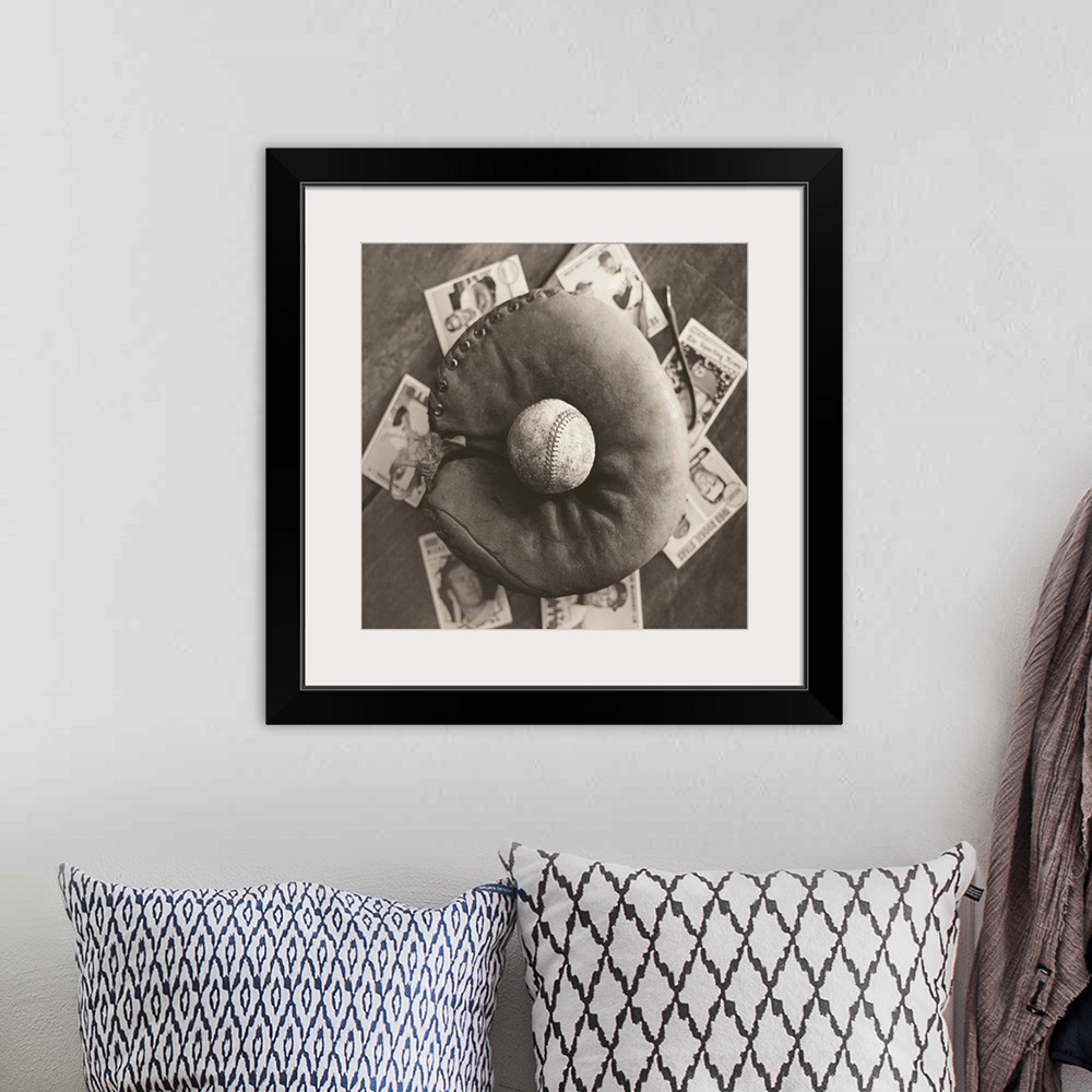 A bohemian room featuring Square sepia toned photograph of a worn baseball in an old mitt and vintage baseball cards behind...