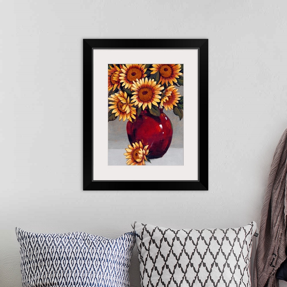 A bohemian room featuring A painting of vibrant yellow sunflowers sitting in a deep red vase against a gray background.