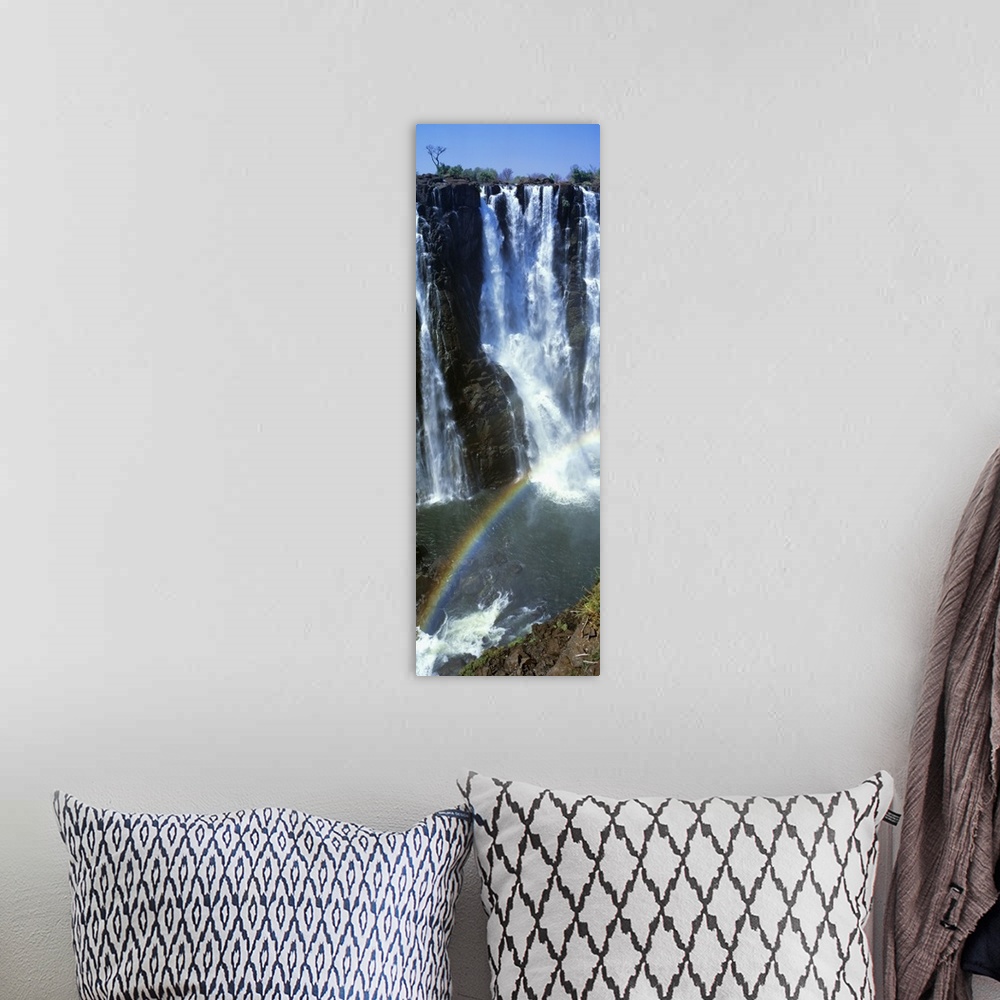 A bohemian room featuring A vertical panoramic piece of an immense waterfall with a rainbow stretching across the bottom of...