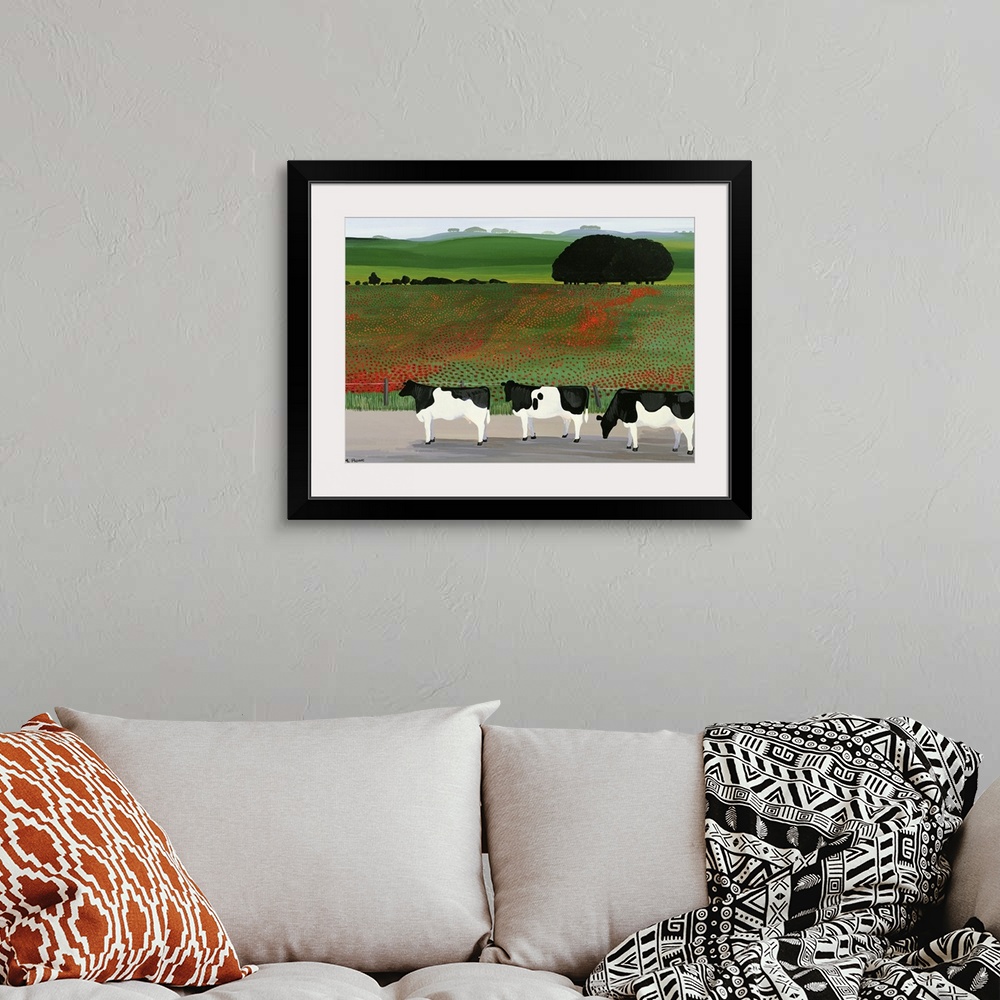 A bohemian room featuring Large artwork on a horizontal canvas of three cows standing in front of a fenced off field of pop...