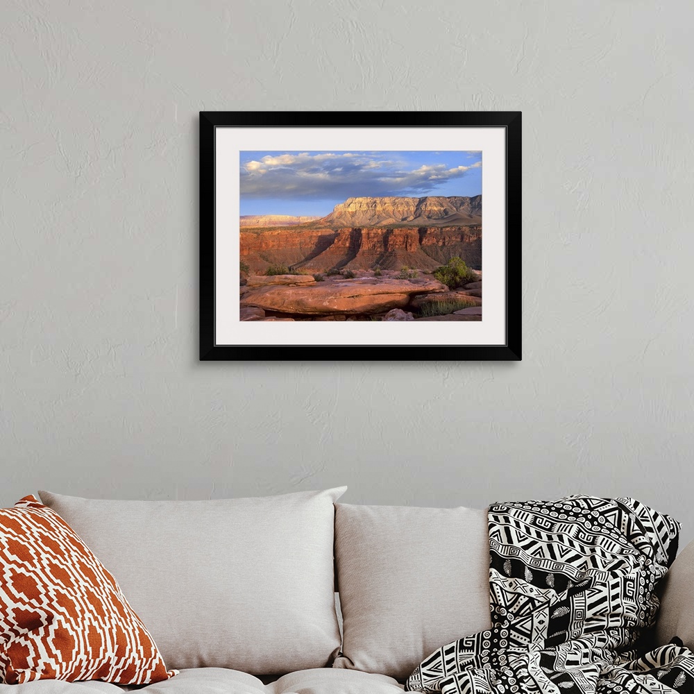 A bohemian room featuring Big landscape photograph of Aubrey Cliffs in the sunlight, beneath a cloudy blue sky, taken from ...