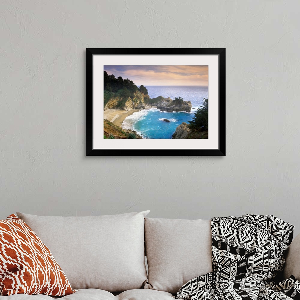 A bohemian room featuring This scenic photograph shows a rocky landscape surrounding a sandy beach and waves washing up on ...