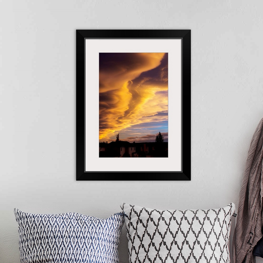 A bohemian room featuring Dramatic colourful clouds at sunset with interesting formations and some blue sky with houses in ...