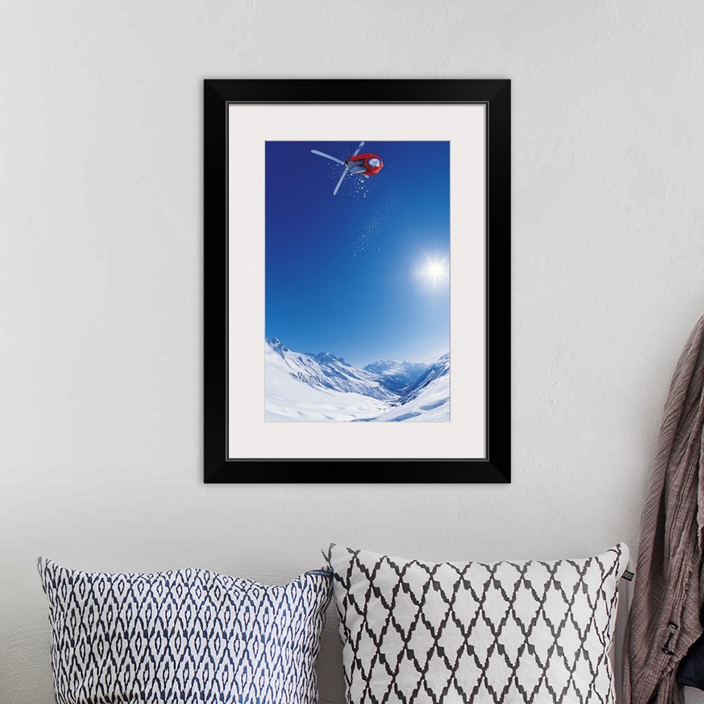 A bohemian room featuring Vertical photo of a man crossing his skis on as he flies through the air as the sun shines down o...