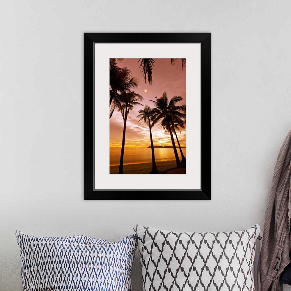 A bohemian room featuring The silhouetted of palm trees on a beach arch into the sky at sunset reaching towards the moon wh...