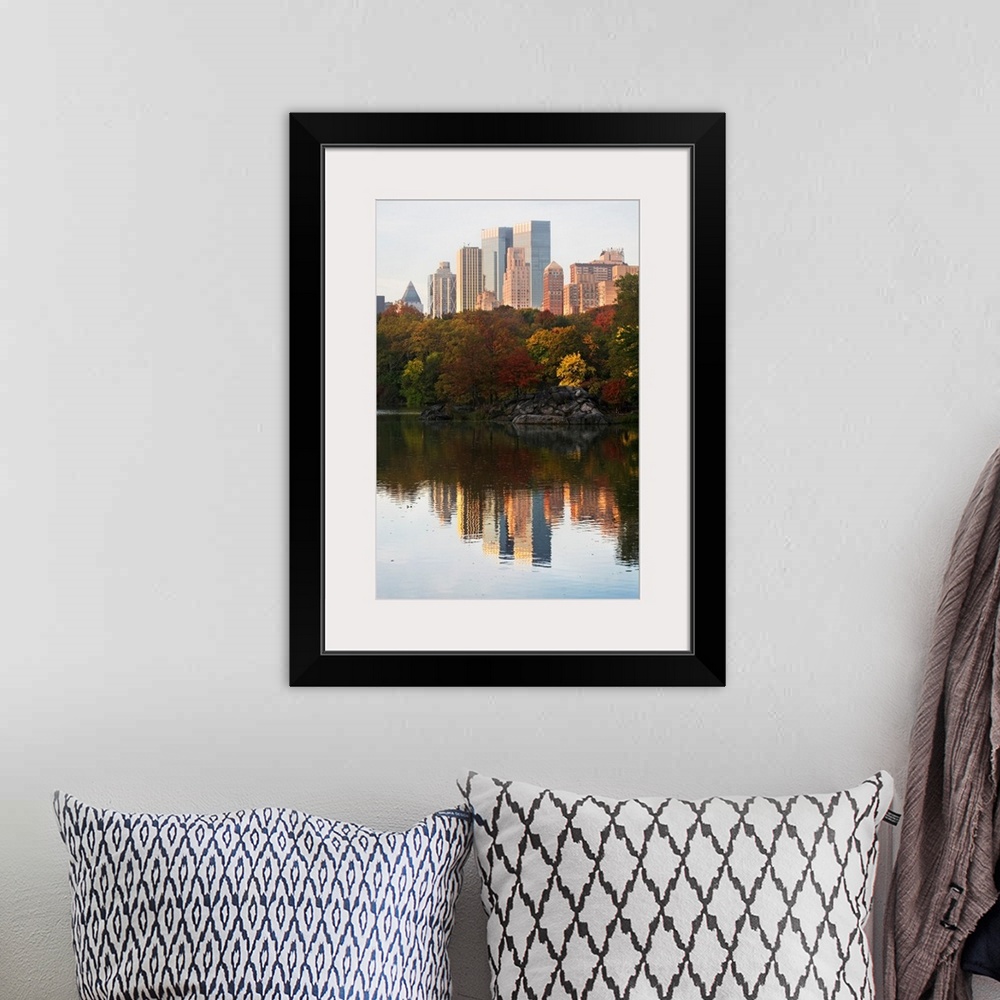 A bohemian room featuring This is a vertical photograph of autumn trees and skyscrapers reflecting in the calm waters of th...