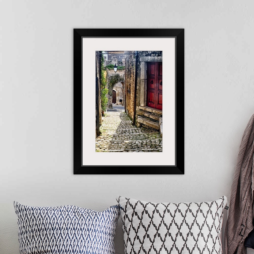 A bohemian room featuring Cobblestone street in Sermoneta, Italy, with a red door on the side.