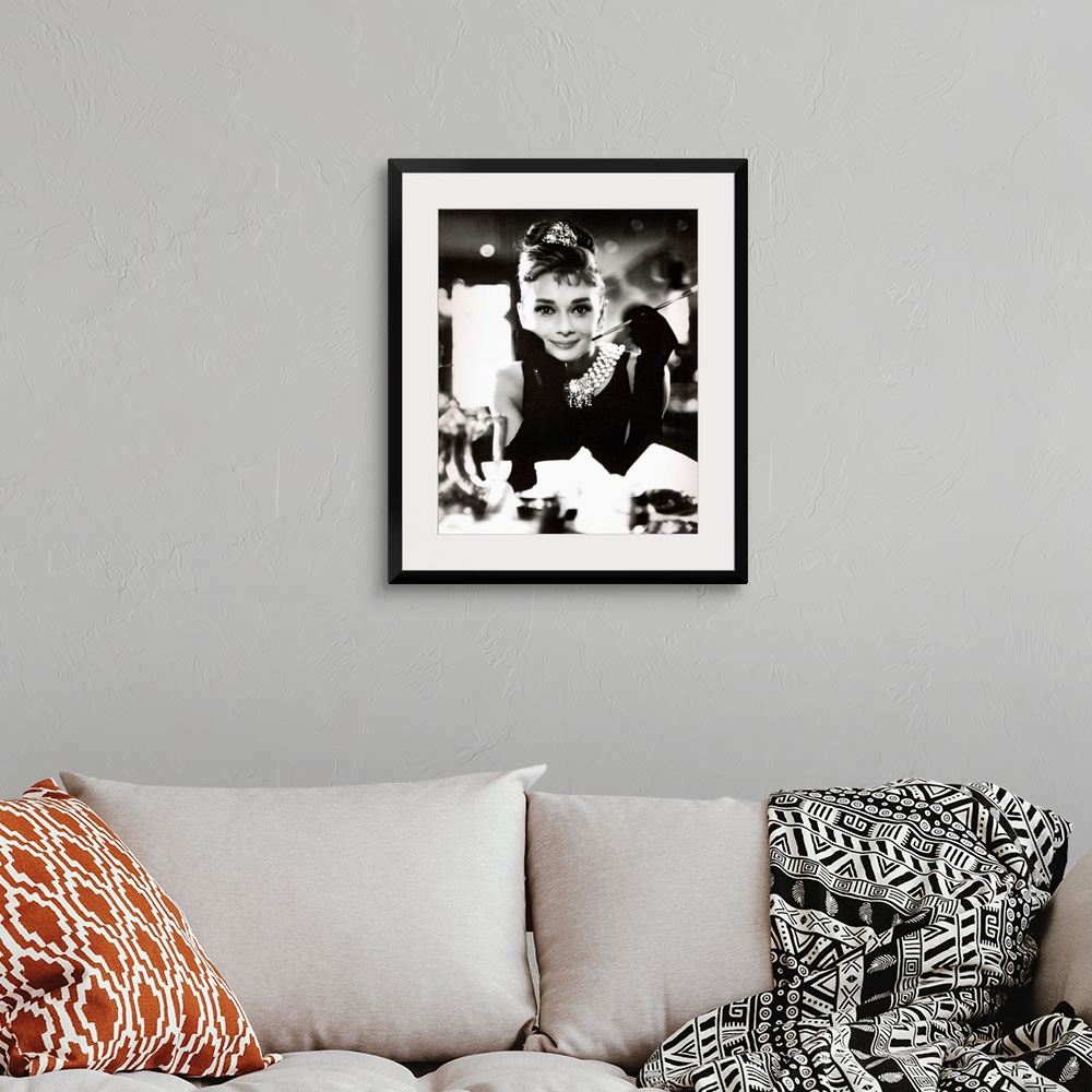 A bohemian room featuring Classic iconic photograph of Audrey Hepburn sitting at a table holding a cigarettte and smiling.