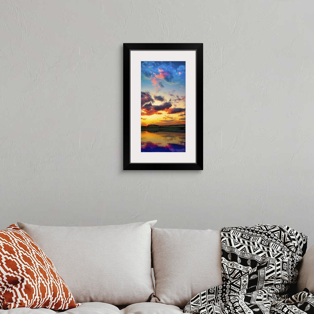 A bohemian room featuring A tall vertical panorama of a sunset reflection on a lake with red and purple clouds.