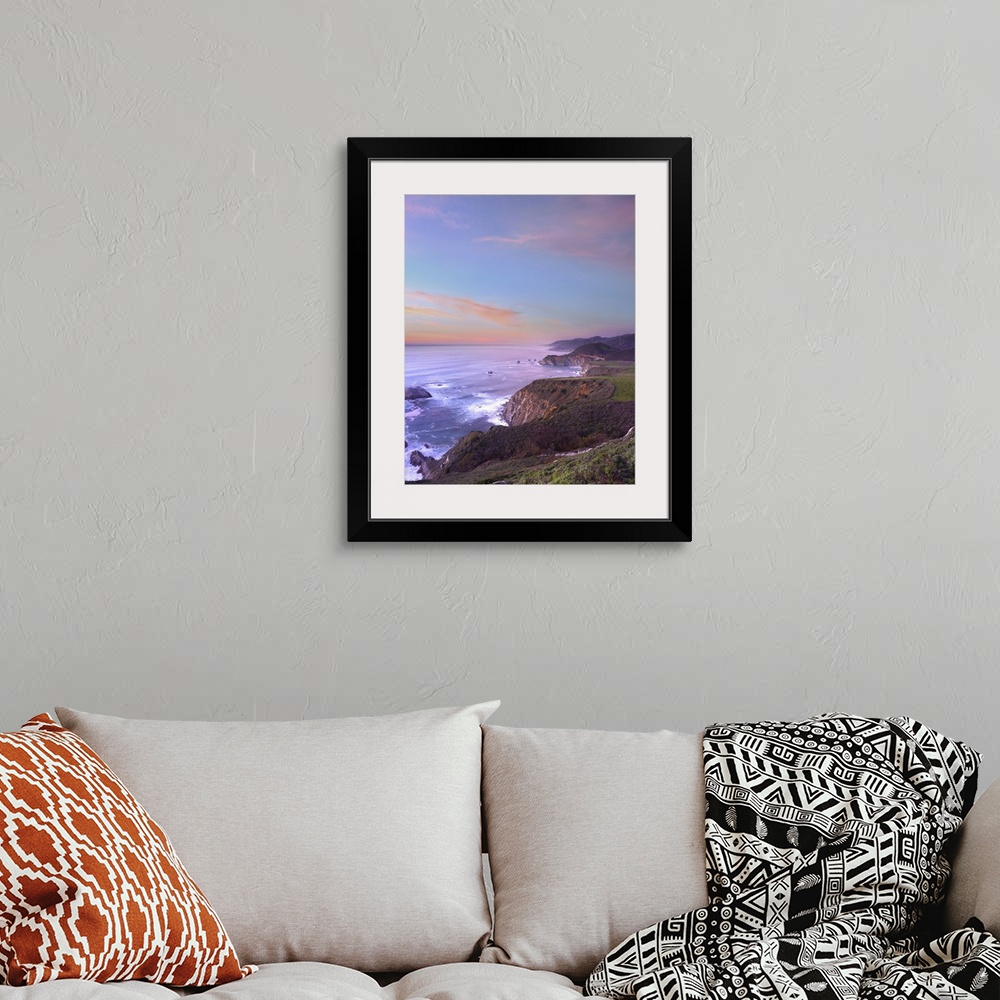 A bohemian room featuring Photograph of rocky cliff edge with crashing waves under a colorful cloudy sky.