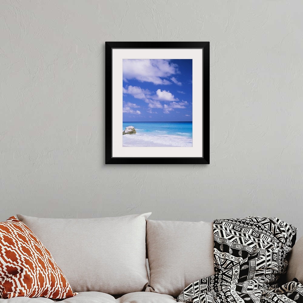 A bohemian room featuring Large photograph displays a lone rock sitting on a beach, while the waves of a sea begin to crash...