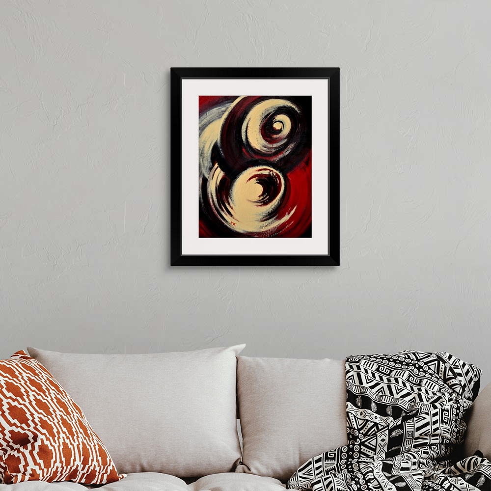 A bohemian room featuring A vertical abstract painting of two large swirls of color in beige, black and red.