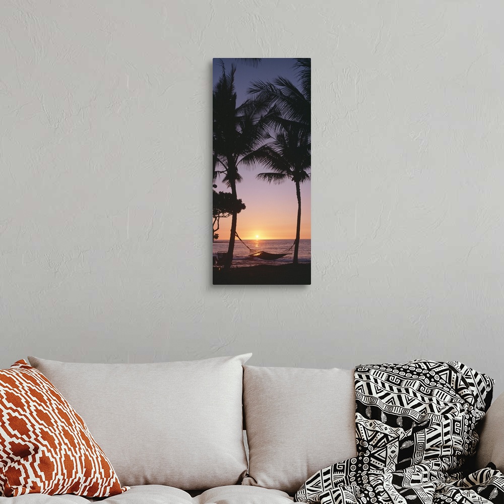 A bohemian room featuring Vertical panoramic of two tall palm trees with hammock on beach at sunset.