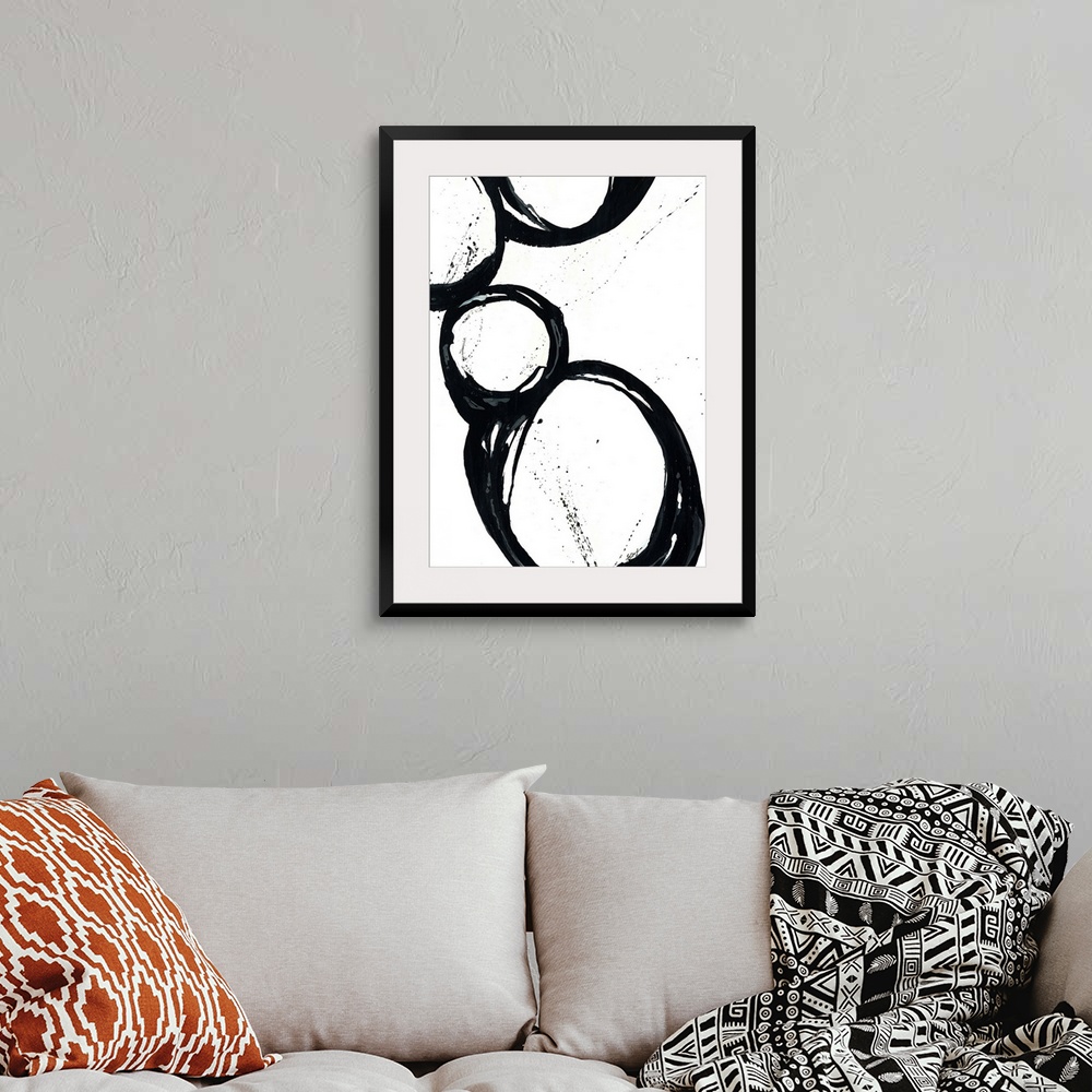 A bohemian room featuring Large vertical abstract modern artwork of different sized circular designs on a blank background.