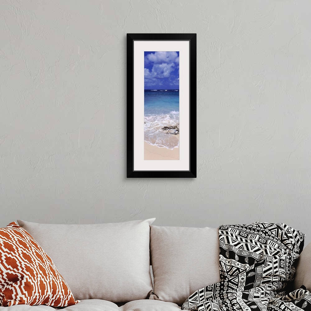 A bohemian room featuring Vertical, large photograph of clear blue waters hitting the beach beneath a blue sky with billowi...