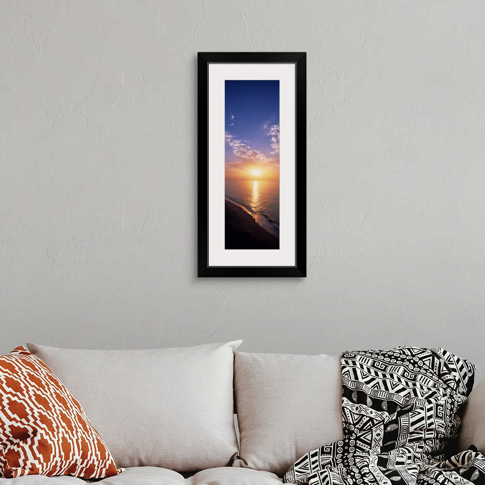 A bohemian room featuring Vertical panorama of the sun rising on the horizon of the Atlantic ocean, as seen from a sandy be...