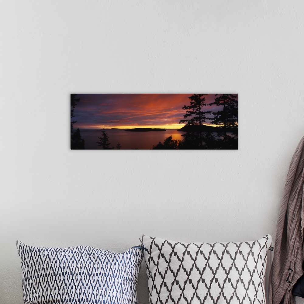 A bohemian room featuring Large, landscape photograph of vibrant clouds in the sky as the sun sets over the Rosario Strait,...