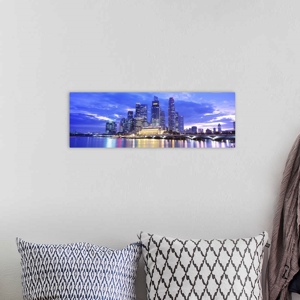 A bohemian room featuring A large panoramic photograph taken of a skyline in Singapore during the evening with all of the b...