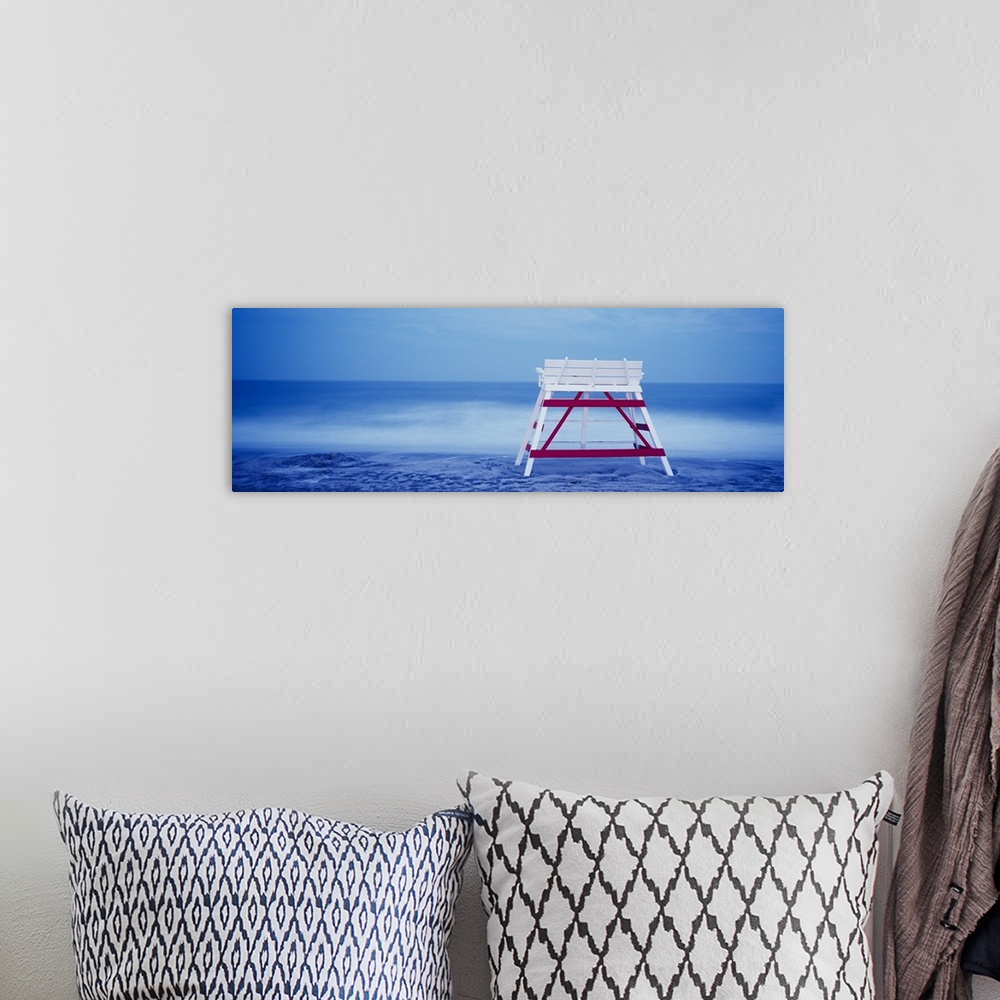 A bohemian room featuring Panoramic photograph on a big canvas of the back of an empty, wooden lifeguard chair sitting on t...