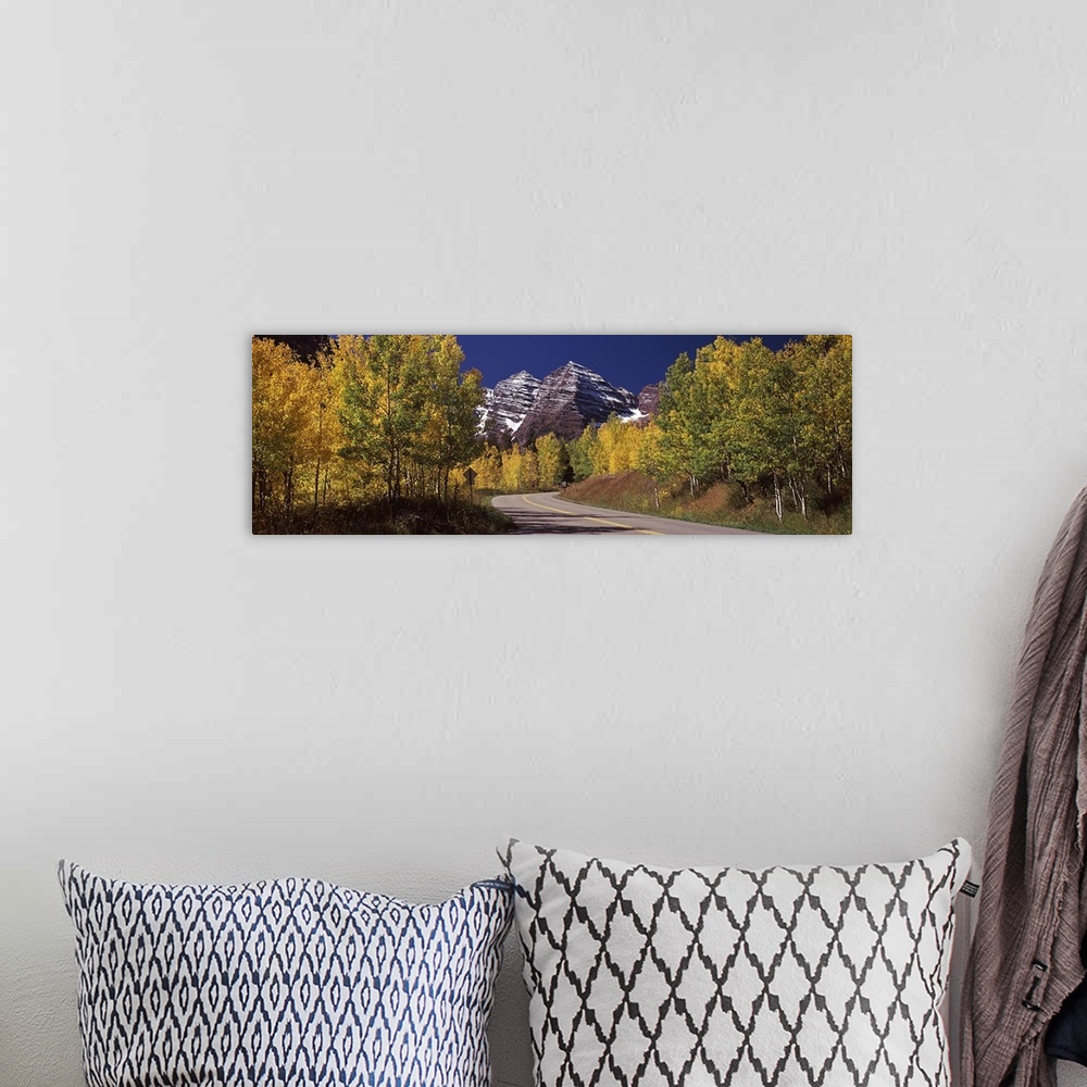 A bohemian room featuring Large, horizontal photograph of a road winding through a fall colored forest, the Maroon Bells in...