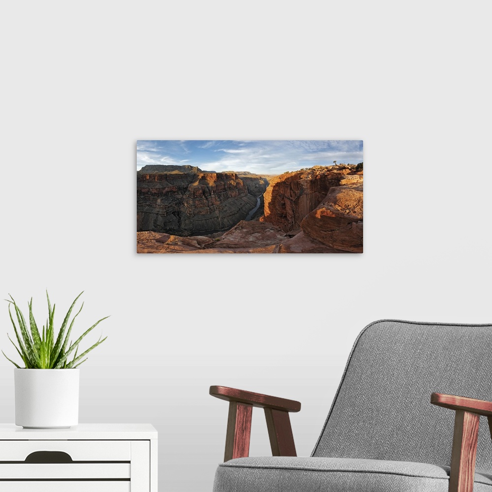 A modern room featuring Large canvas photo of Grand Canyon cliffs draped in sunlight and shadows with a river running thr...