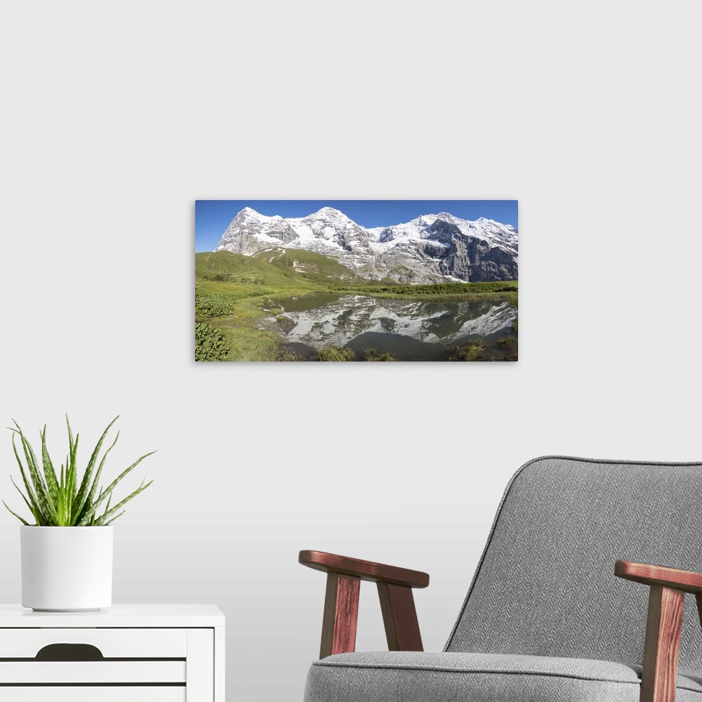 A modern room featuring Panorama of snowy peaks reflected in the alpine lake, Wengernalp, Wengen, Bernese Oberland, Canto...