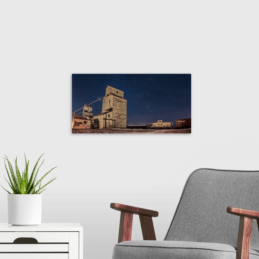 A modern room featuring Orion and the winter stars rising behind grain elevators in Mossleigh, Canada.