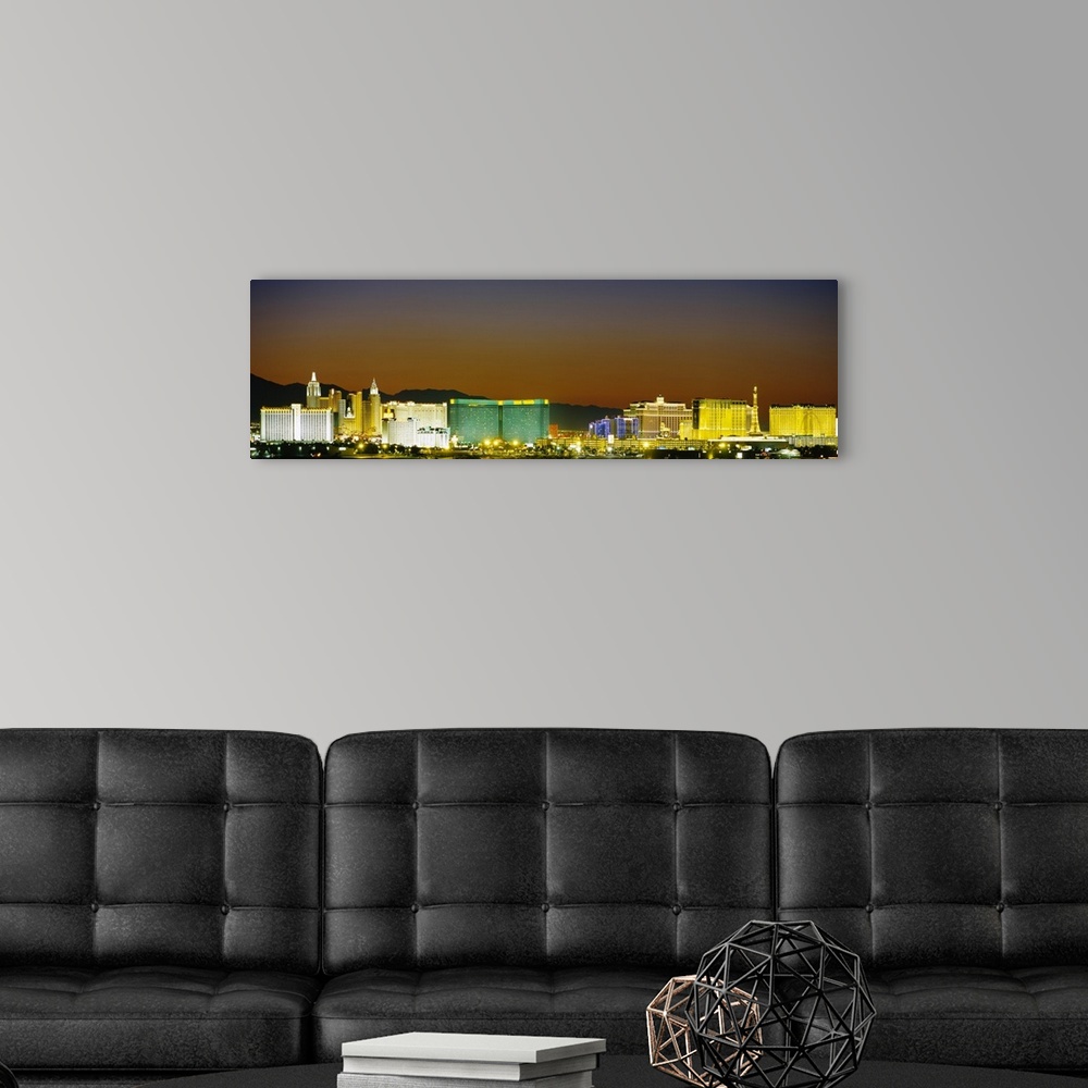 A modern room featuring Wide angle, distant photograph of the brightly lit Las Vegas skyline, at night.