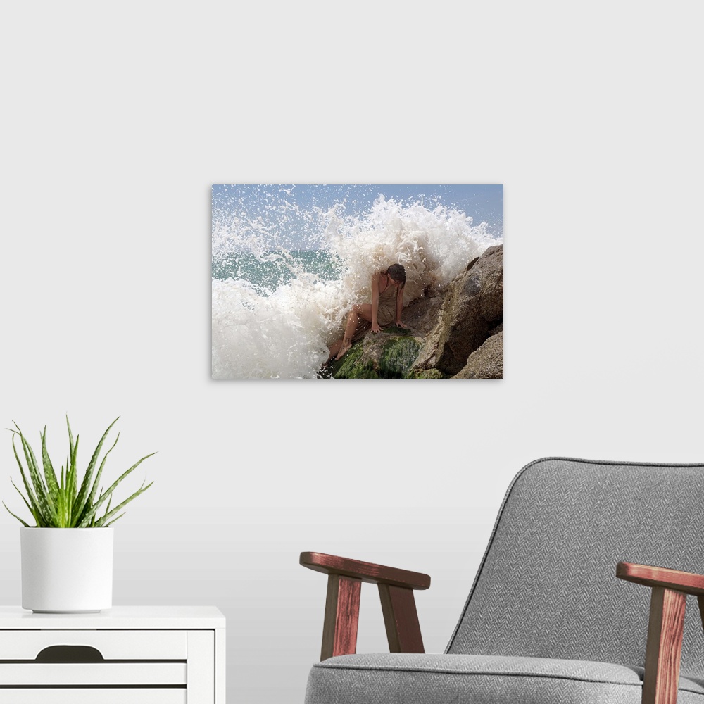 A modern room featuring A model on ocean rocks braces herself against the crashing waves.