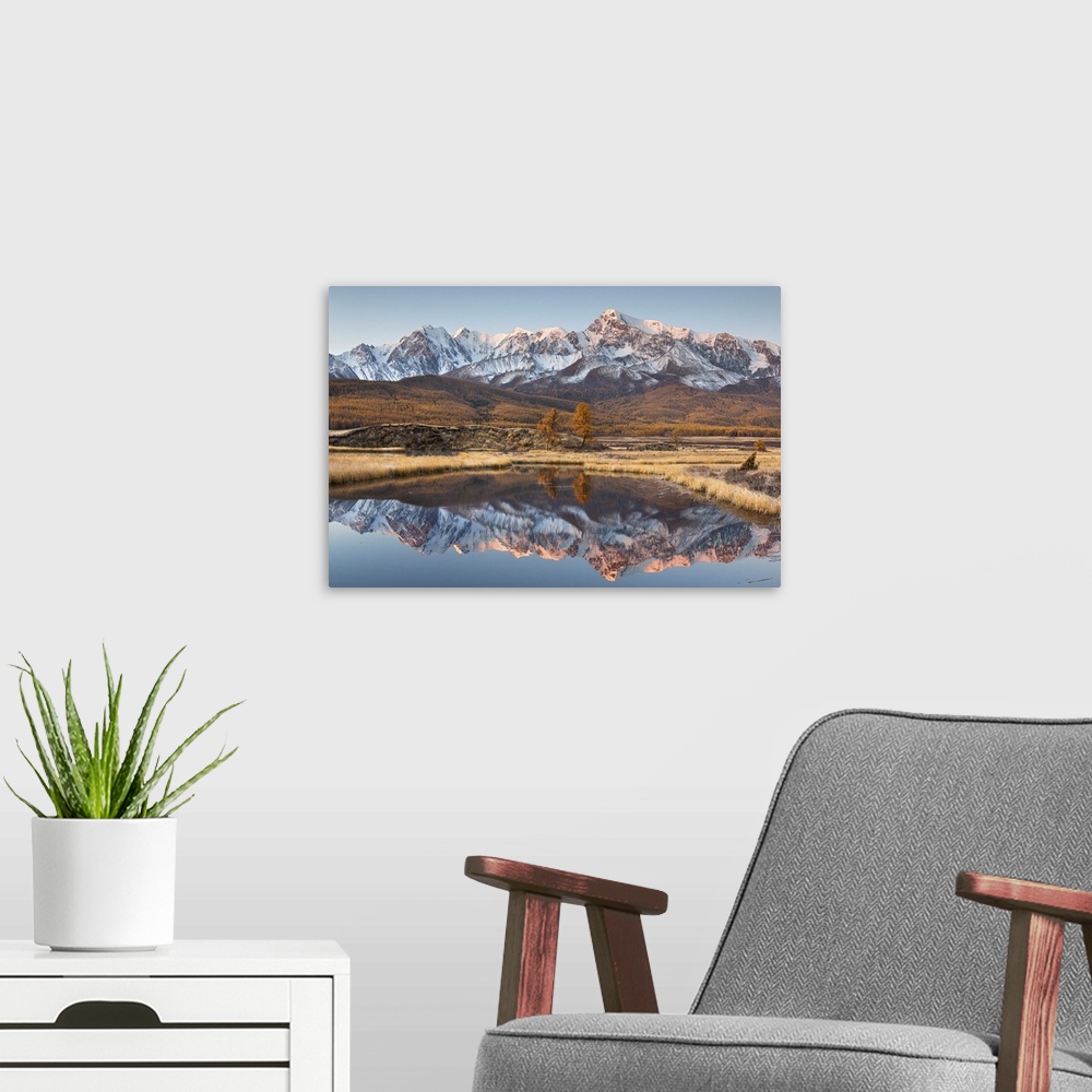 A modern room featuring Snowy mountain range in Russia with sunset glow on the peaks, reflected in the lake below.